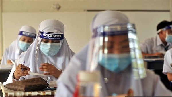 Học sinh Malaysia đeo kính chắn giọt bắn trong lớp học trước khi trường đóng cửa.