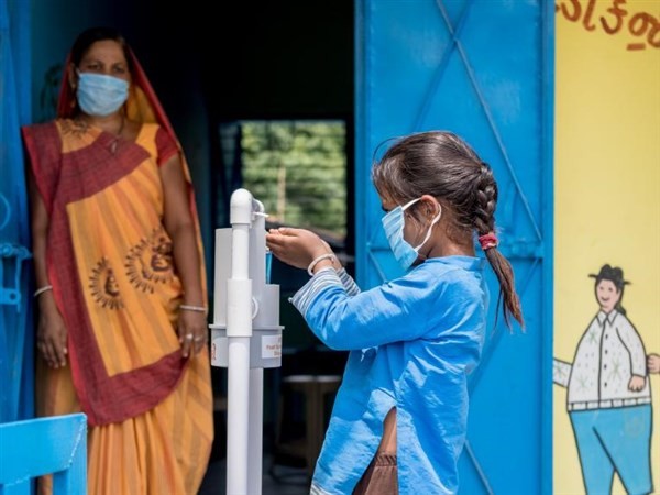 Học sinh Ấn Độ sát khuẩn tay trước khi vào trường học.