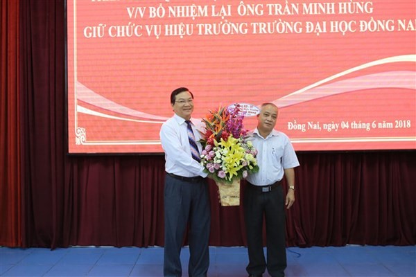 Ông Trần Minh Hùng (trái) nhận hoa chúc mừng khi được tái bổ nhiệm Hiệu trưởng Trường ĐH Đồng Nai (2018) và ông Phan Văn Thanh (cựu Trưởng phòng KHTC trường, vừa bị kỷ luật bằng hình thức khai trừ Đảng).