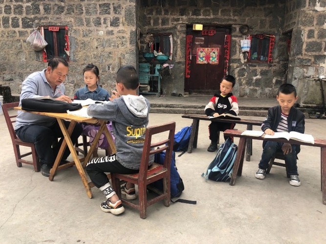 Thầy Zhang (trái) dạy học sinh tập đọc, viết.