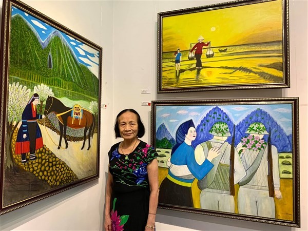 Bà giáo Nguyễn Ngọc Dậu bên những tác phẩm của mình tại triển lãm tranh. 
