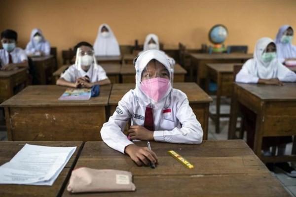 Học sinh Indonesia đeo kính chắn giọt bắn khi trở lại trường.
