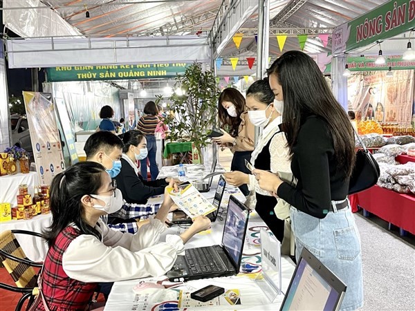Nhân viên hướng dẫn người dân sử dụng ứng dụng TMĐT để mua sắm sản phẩm hàng hóa trong chương trình tuần bán hàng trực tuyến tại Uông Bí, Quảng Ninh.