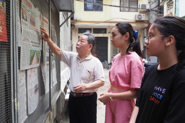 Ông Nguyễn Văn Tích hướng dẫn dán và đọc báo cho các em học sinh.