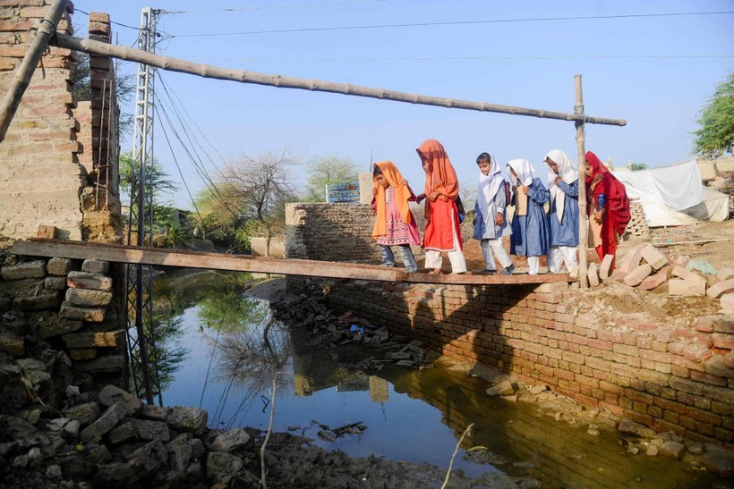 Trẻ em Pakistan băng qua một 'cây cầu' tạm để đến trường.