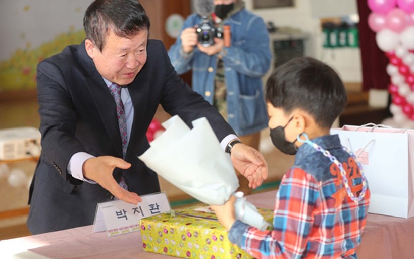 Park Ji Hwan (phải) nhận hoa và quà từ hiệu trưởng trong lễ khai giảng tại Trường Tiểu học Gusong, Hàn Quốc.