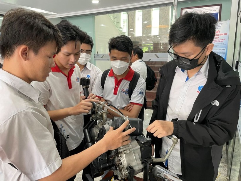 Trần Lê Phước (trái) giới thiệu hệ thống chống ngập tích hợp vào xe máy với các sinh viên cùng trường.