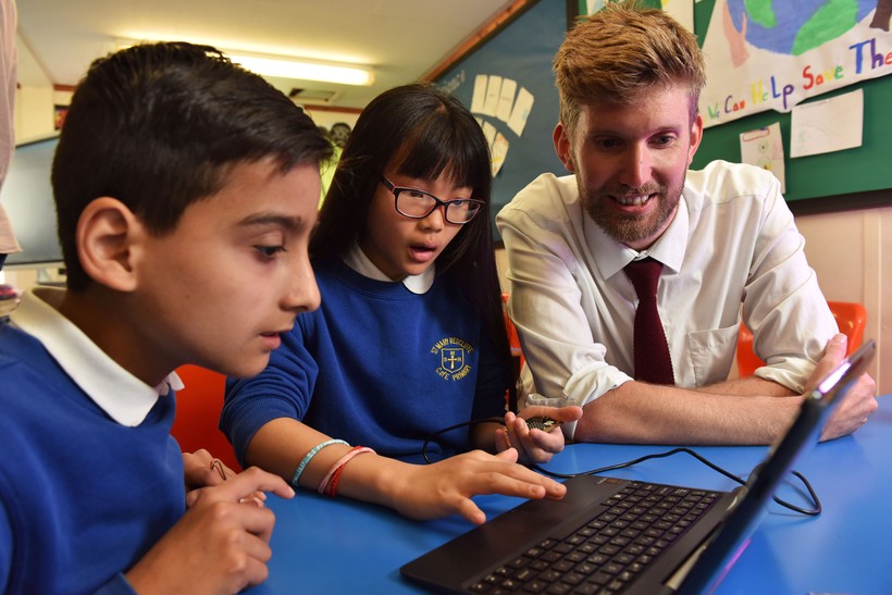 Giáo viên Anh hướng dẫn học sinh làm quen với máy tính.