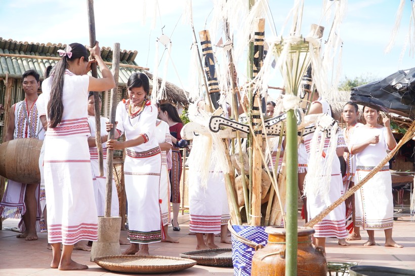Những người phụ nữ trong trang phục truyền thống giã lúa mới.