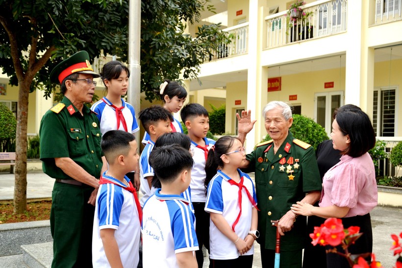 Ông Bế Văn Sâm (người giơ tay) đang kể chuyện lịch sử cho các em học sinh.