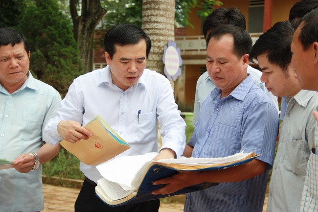 Ông Nguyễn Minh Tường  cùng các cán bộ  xem xét hồ sơ, sổ sách bị hỏng do ngập nước. 