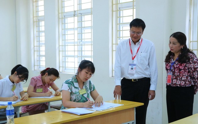 Thứ trưởng Lê Hải An cùng bà Vũ Liên Oanh thị sát công tác chấm thi tại Ban chấm thi tự luận. Ảnh: Việt Hà