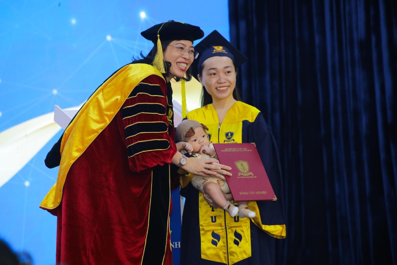 Hình ảnh hết sức dễ thương khi em bé theo mẹ lên nhận bằng tốt nghiệp.