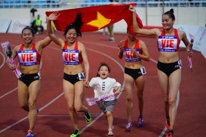 Nguyễn Thị Huyền dắt tay con gái trong lúc cùng các đồng đội mừng Huy chương Vàng nội dung 4x400m nữ tối 18/5.