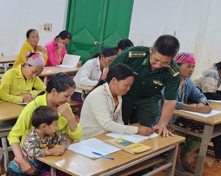 Trung tá Tòng Văn Xum đang dạy chữ cho bà con bản Huổi Pá.