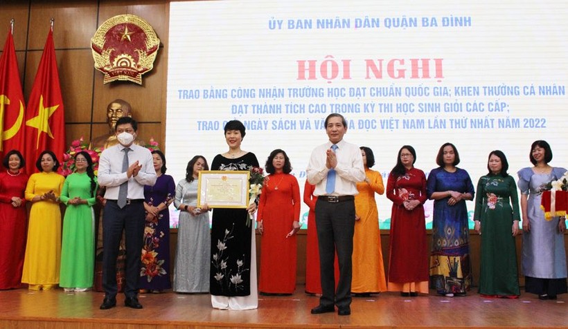 Bí thư Quận ủy Hoàng Minh Dũng Tiến (bên phải) và Chủ tịch UBND quận trao bằng khen cho giáo viên. 