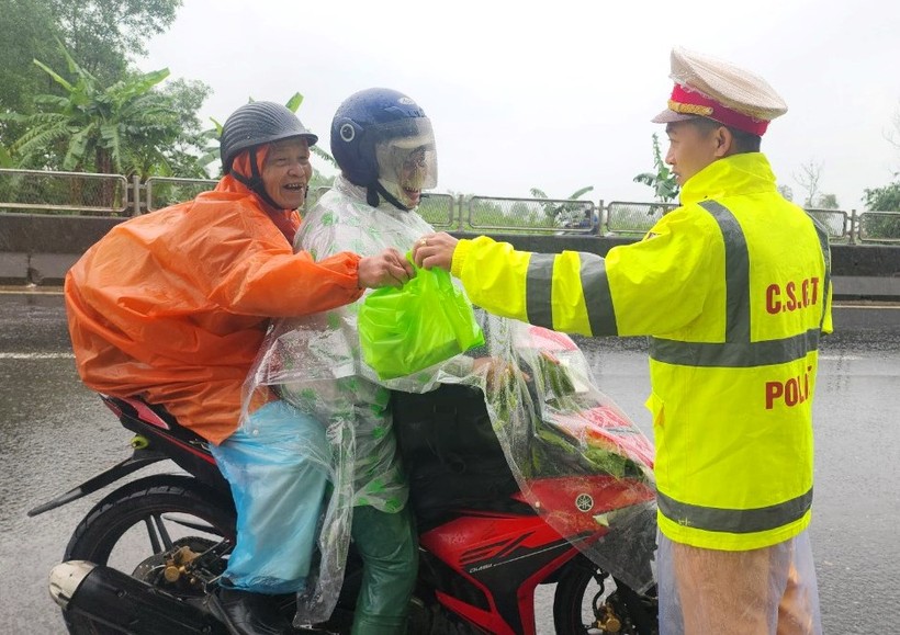 Các chiến sĩ Trạm CSGT Phú Lộc, Công an tỉnh thừa Thiên - Huế phát nước uống, thức ăn miễn phí cho người dân trên đường vào Nam làm việc trở lại sau Tết (Ảnh: T.H).