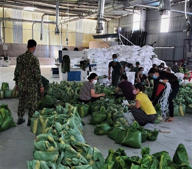Lực lượng quân đội tích cực hỗ trợ chính quyền địa phương chuẩn bị gạo, thực phẩm để phát cho dân tại 4 phường bị phong toả ở thành phố Thuận An, tỉnh Bình Dương. Ảnh: TTXVN.