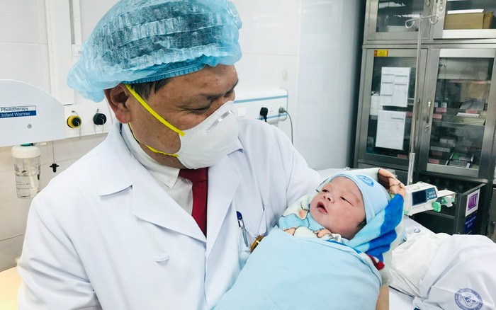 Giám đốc Bệnh viện Phụ sản TƯ Trần Danh Cường bế bé Nguyễn Nhật Anh Khôi. em bé đầu tiên chào đời tại bệnh viện năm 2022. Ảnh: HNM.