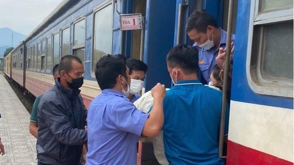 Nhân viên đường sắt hỗ trợ đưa mẹ con sản phụ xuống tàu tại ga Đồng Lê. Ảnh: SGGP.