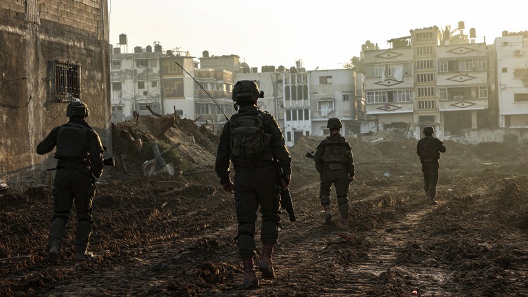 Binh sĩ Israel đi ngang qua các tòa nhà bị hư hại trong một chiến dịch quân sự ở phía bắc Dải Gaza