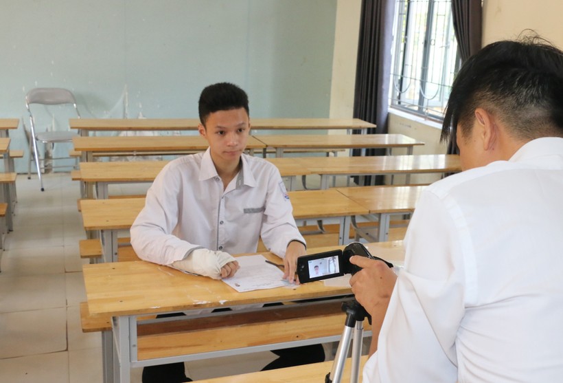 Thí sinh Nguyễn Công Đạt (điểm thi Trường THPT Nghi Lộc 3, huyện Nghi Lộc, Nghệ An) thi môn Ngữ văn tại phòng riêng với máy quay ghi hình quá trình làm bài. Ảnh: Hồ Lài.