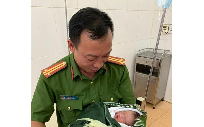 Trung tá Lò Văn Ức đang bế cháu bé tại Bệnh viện Đa khoa huyện Thuận Châu