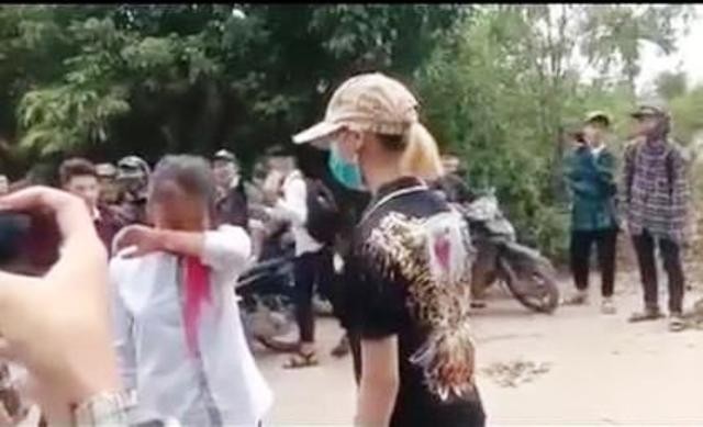 Nữ sinh đeo khăn quàng đỏ bị một nữ thanh niên chặn đường hành hung. Ảnh cắt từ clip.