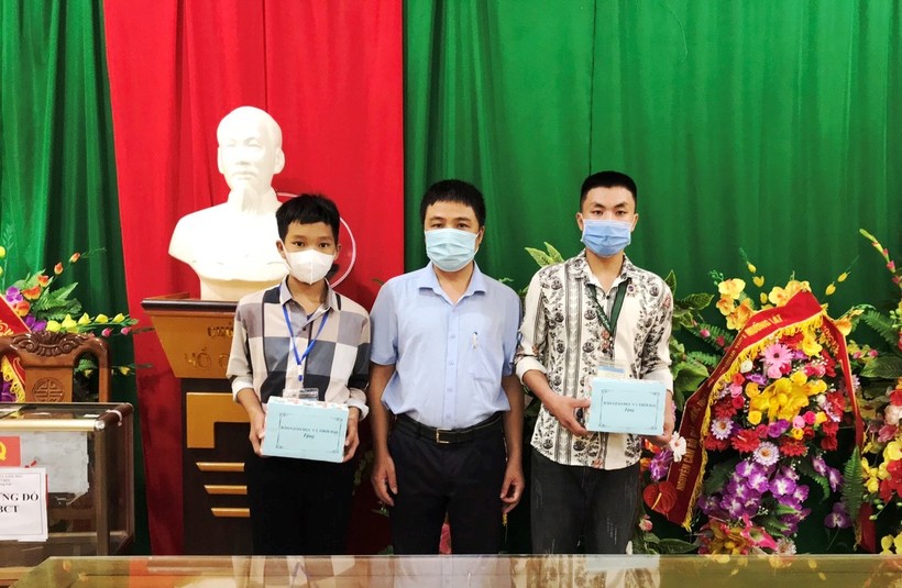 Thầy Trần Anh Văn – Hiệu trưởng Trường THPT Mường Lát trao điện thoại mới cho em Thao Văn Chá (ảnh trái) và em Đinh Công Tú.