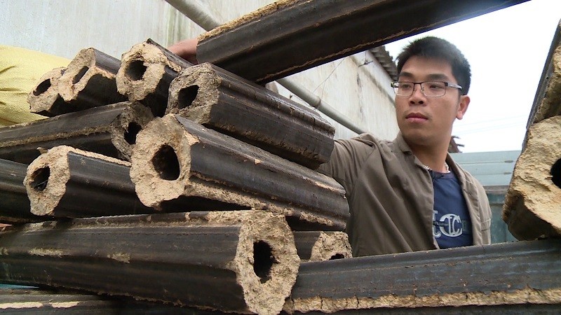 Nguyễn Hữu Dũng bên sản phẩm than vỏ trấu của mình. Ảnh: NVCC