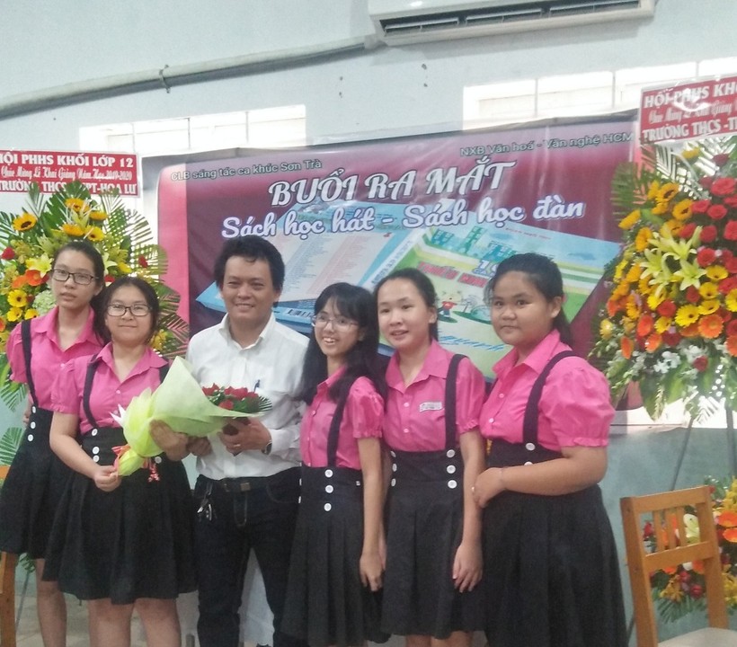 Thầy giáo Đoàn Ngô Tĩnh nhận hoa chúc mừng của học trò trong buổi ra mắt tuyển tập 100 ca khúc thiếu nhi