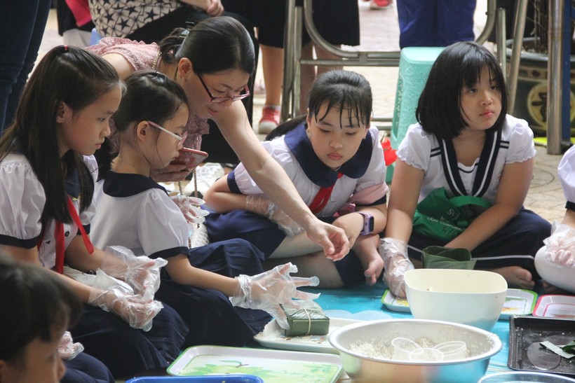 Học sinh tiểu học tại TP.HCM học gói bánh chưng trong Ngày hội xuân. Ảnh minh hoạ 