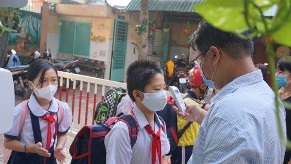 Học sinh Trường TH Trần Quang Khải, Quận Gò Vấp được kiểm tra thân nhiệt trước khi vào trường. Ảnh minh hoạ 