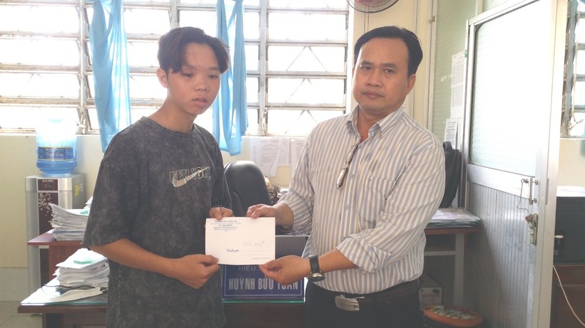 Thầy Huỳnh Bửu Tuấn, Hiệu trưởng Trường THPT Vĩnh Hải trao số tiền từ bạn đọc Báo GD&TĐ giúp đỡ cho em Lê Quốc Phi.