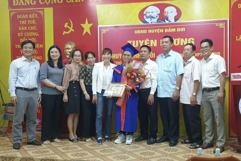 Em Huỳnh Anh Khôi cùng lãnh đạo UBND huyện, gia đình và thầy cô tại lễ tuyên dương. Ảnh: K. Nhiên.