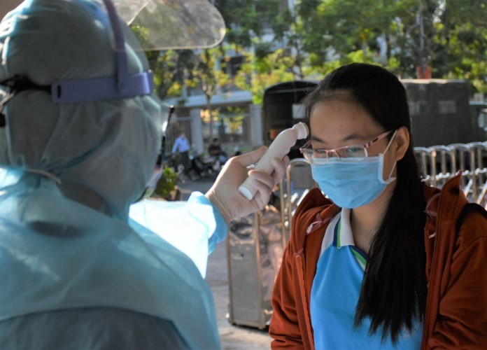 Các thí sinh chuẩn bị bước vào Kỳ thi tốt nghiệp THPT 2020 tại Đà Nẵng được cán bộ y tế đo thân nhiệt trước khi vào phòng nhận phiếu thông tin xét nghiệm.