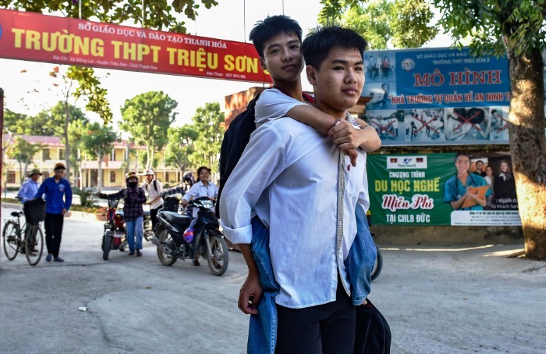 Ngô Văn Hiếu cõng Nguyễn Tất Minh tới trường.