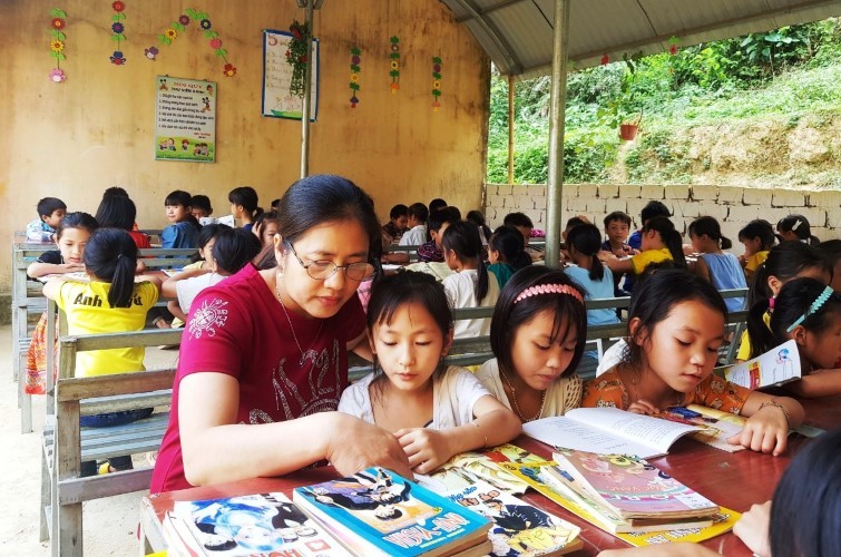 Cô Phạm Thị Hương hướng dẫn học trò của mình trong giờ đọc sách ở thư viện xanh, tại điểm trường bản Giá. 