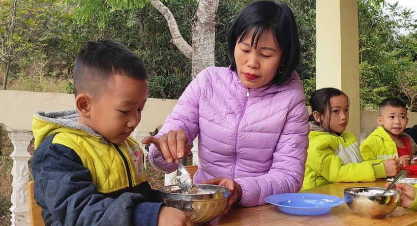Bé Vi Thanh Hà đang được cô giáo chăm sóc trong bữa ăn tại trường.