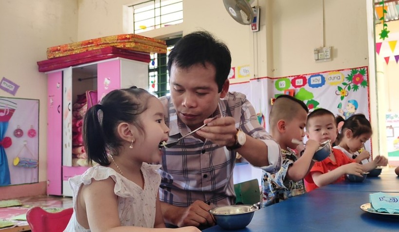 Thầy giáo Trịnh Hồng Quân – Hiệu trưởng Trường Mầm non Thành Sơn (Bá Thước, Thanh Hóa) đang cho trẻ ăn trưa tại trường.