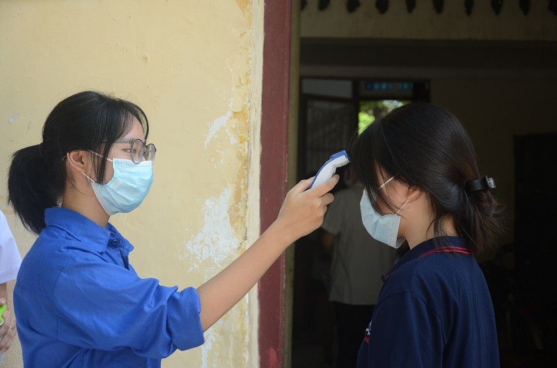 Thanh niên tình nguyện hỗ trợ đo thân nhiệt cho thí sinh chiều 6/7, tại điểm thi Trường THPT Trần Phú (Hoàn Kiếm Hà Nội). Ảnh: TG