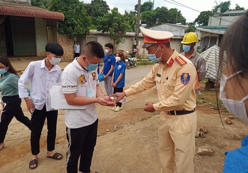 Các đồng chí CSGT hỗ trợ thí sinh khử khuẩn trước khi rời trường thi tại Sơn La. Ảnh: MT