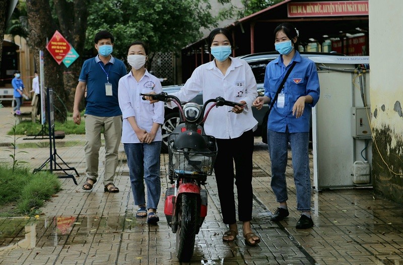 Hình ảnh thí sinh Đồng Thị Luyến dắt xe sau khi đèo bạn Ngô Thị Lan Dung (bị khuyết tật) đến Điểm thi.