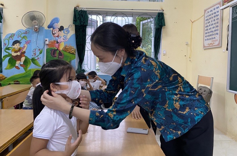 Học sinh lớp 1 huyện Việt Yên được hướng dẫn đeo khẩu trang trong ngày tựu trường.