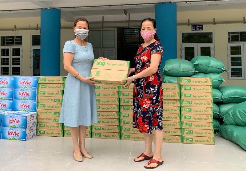 Cô Đinh Phương Anh – Hiệu trưởng Trường THCS Lương Yên (bên trái) tiếp nhận quà của nhà hảo tâm 
để hỗ trợ cho gia đình học sinh khó khăn do ảnh hưởng của dịch Covid-19. Ảnh: NTCC