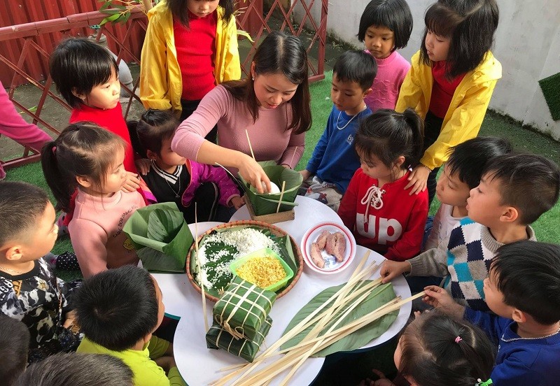 Giáo viên Trường Mầm non Bình Minh (TP Bắc Giang) gói bánh chưng Tết và giới thiệu văn hóa Tết Việt cho học sinh. Ảnh: NTCC