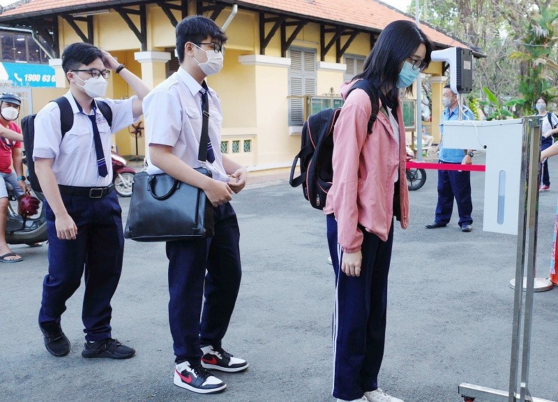 Học sinh đo thân nhiệt và khử khuẩn tay trước khi vào lớp tại Trường THPT Nguyễn Thị Minh Khai, TPHCM.