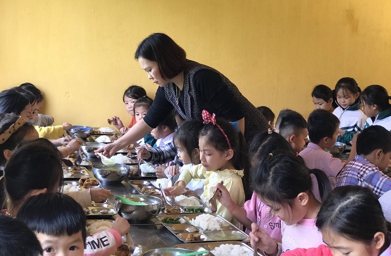 Cô Vũ Thu Hương hỗ trợ học sinh trong bữa ăn bán trú.