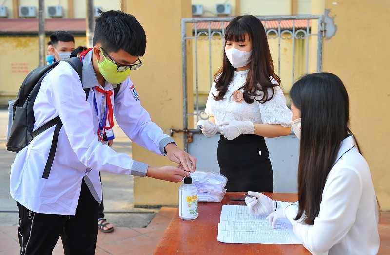 Nhân viên y tế học đường hướng dẫn học sinh Trường THCS Ninh Thành (Ninh Bình) sát khuẩn tay trước khi vào trường.