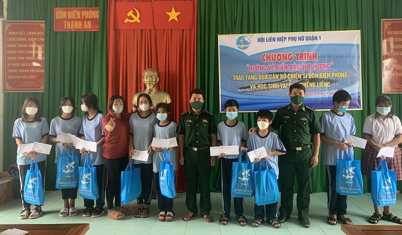 Cán bộ Đồn Biên phòng Thạnh An phối hợp với nhà hảo tâm tặng quà học sinh nghèo. 